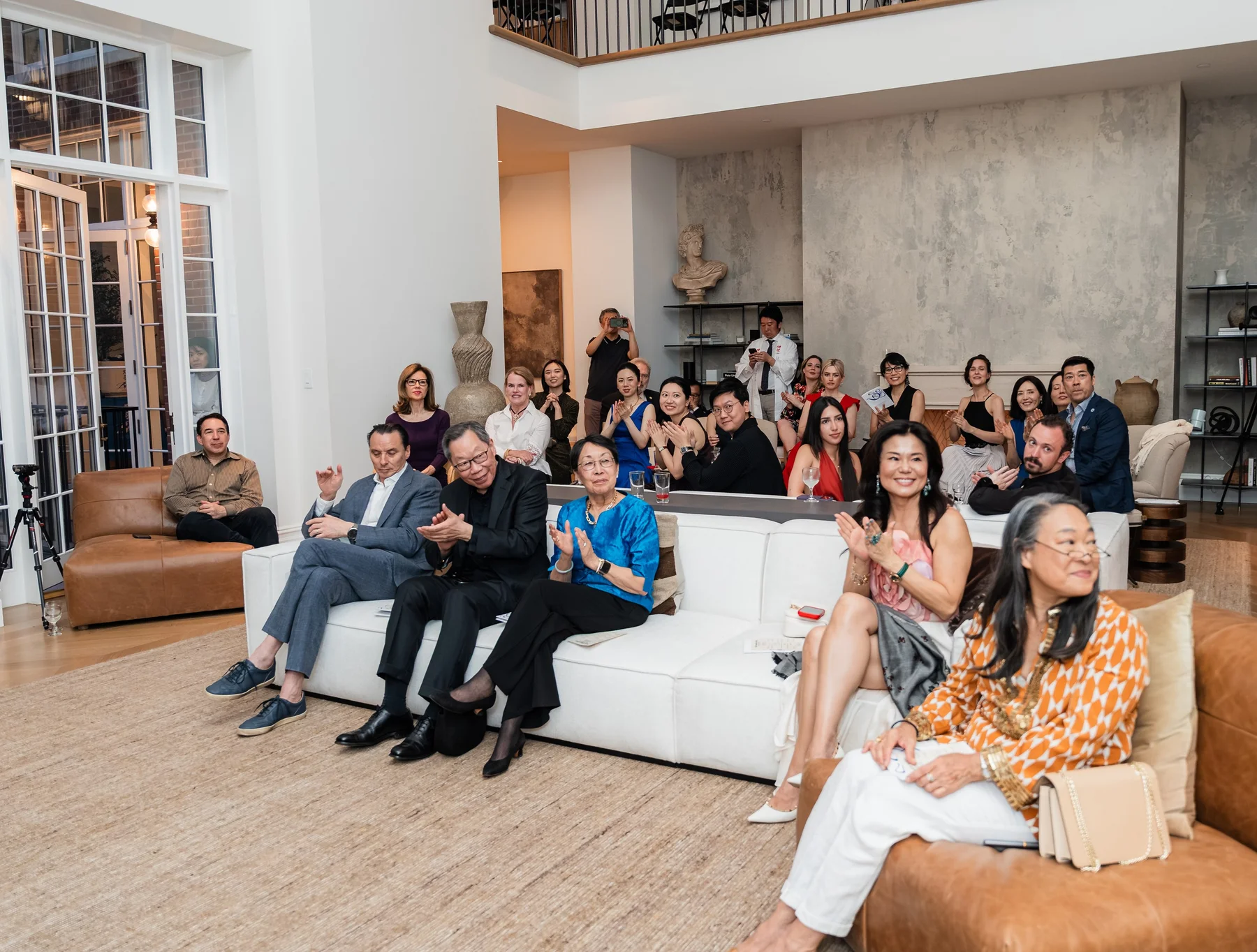 Guests on the sofas at the townhouse salon, applauding
