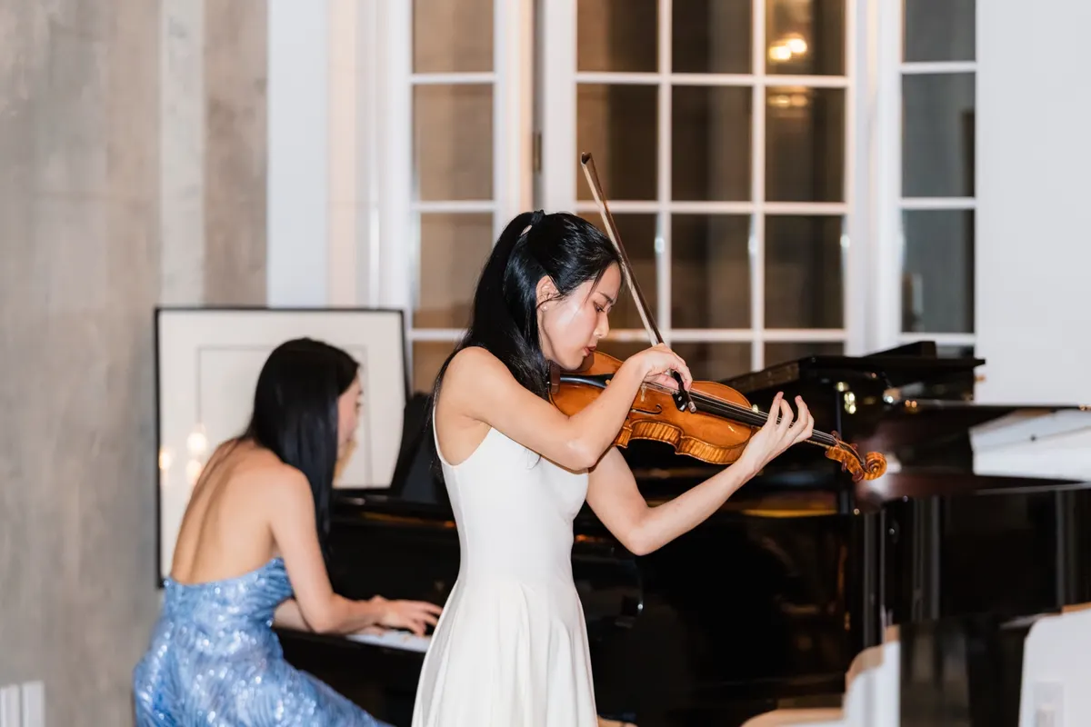 Risa Hokamura playing the violin by the townhouse windows