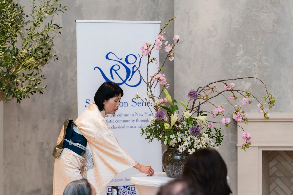 Komi Hatazaki arranging ikebana beside the Sora banner