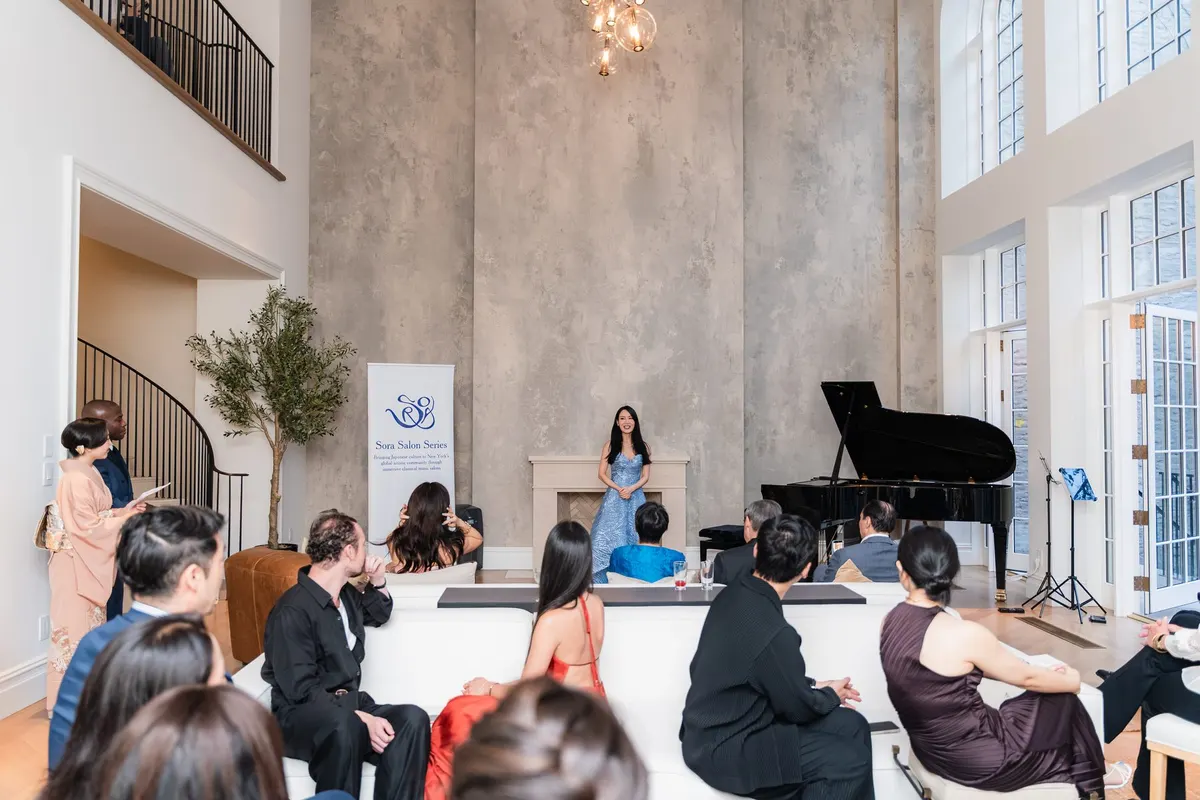 Rieko welcoming the seated audience from the fireplace