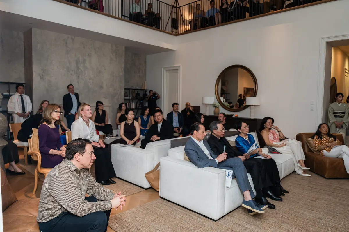 The audience on sofas in the double-height room, more on the balcony
